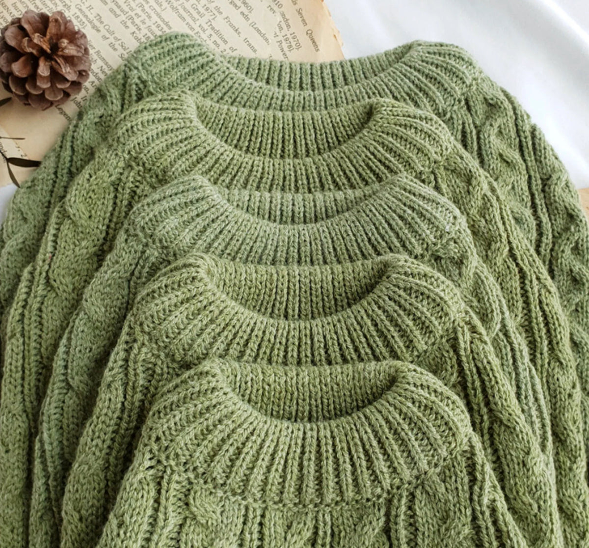 Close-up of olive cable-knit texture and ribbed necklines